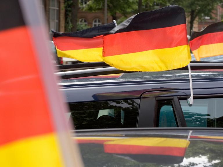 Deutschland-Fahnen wehen an fahrenden Autos.