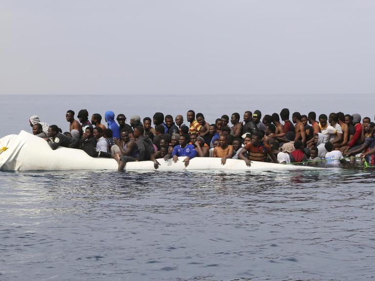 Flüchtlinge warten in einem überfüllten Schlauchboot vor der libyschen Küste auf ihre Rettung aus dem Mittelmeer.