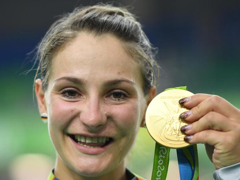 Vier Jahre nach ihrem überraschenden Olympiasieg im Teamsprint gewinnt Kristina Vogel wieder Gold - lächelnd hält sie die Medaille in die Kamera.