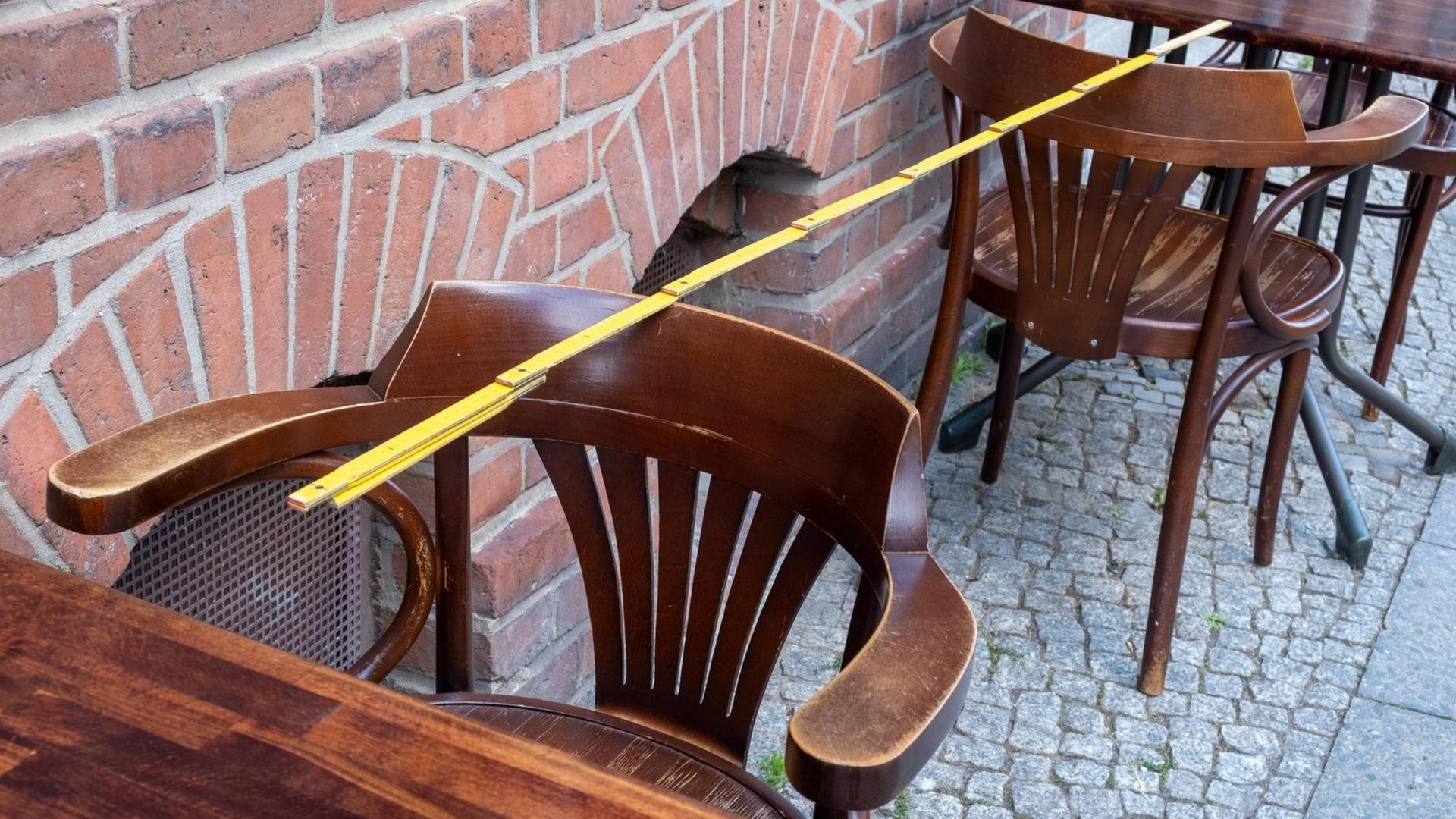 In einem leeren Restaurant liegt ein Zollstock über zwei Tischen und Stühlen, um den Abstand zu messen.