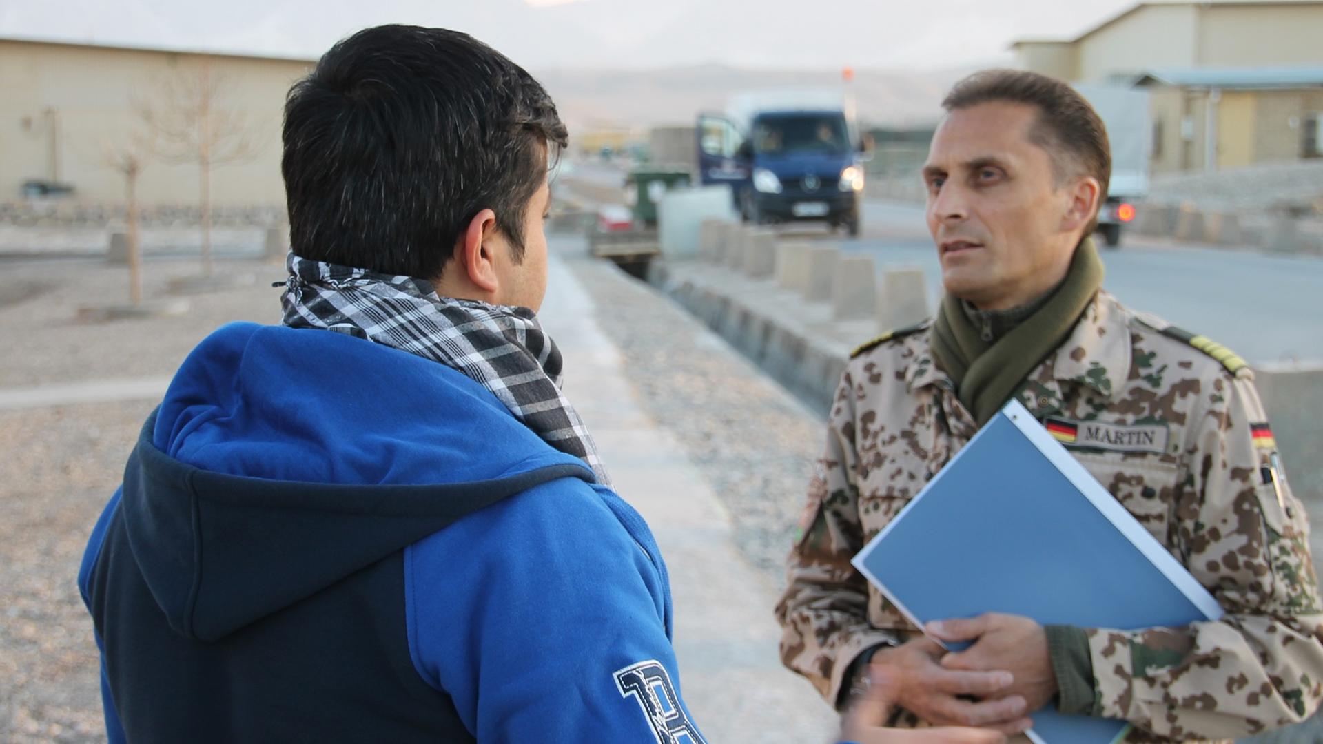 Afghanischer Helfer im Gespräch mit Bundeswehrangehörigem.