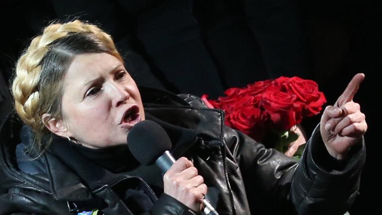 Julia Timoschenko hält im Rollstuhl sitzend eine Rede, in ihrer rechten Hand hält sie ein Mikrofon.