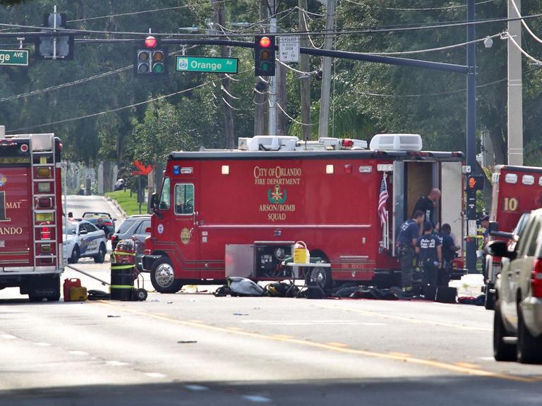 Das Bild zeigt drei rote Feuerwehrautos und Feuerwehrleute auf der Straße vor dem Pulse-Club in Orlando (USA), wo am 12.6.2016 ein Mann 49 Menschen erschoss.