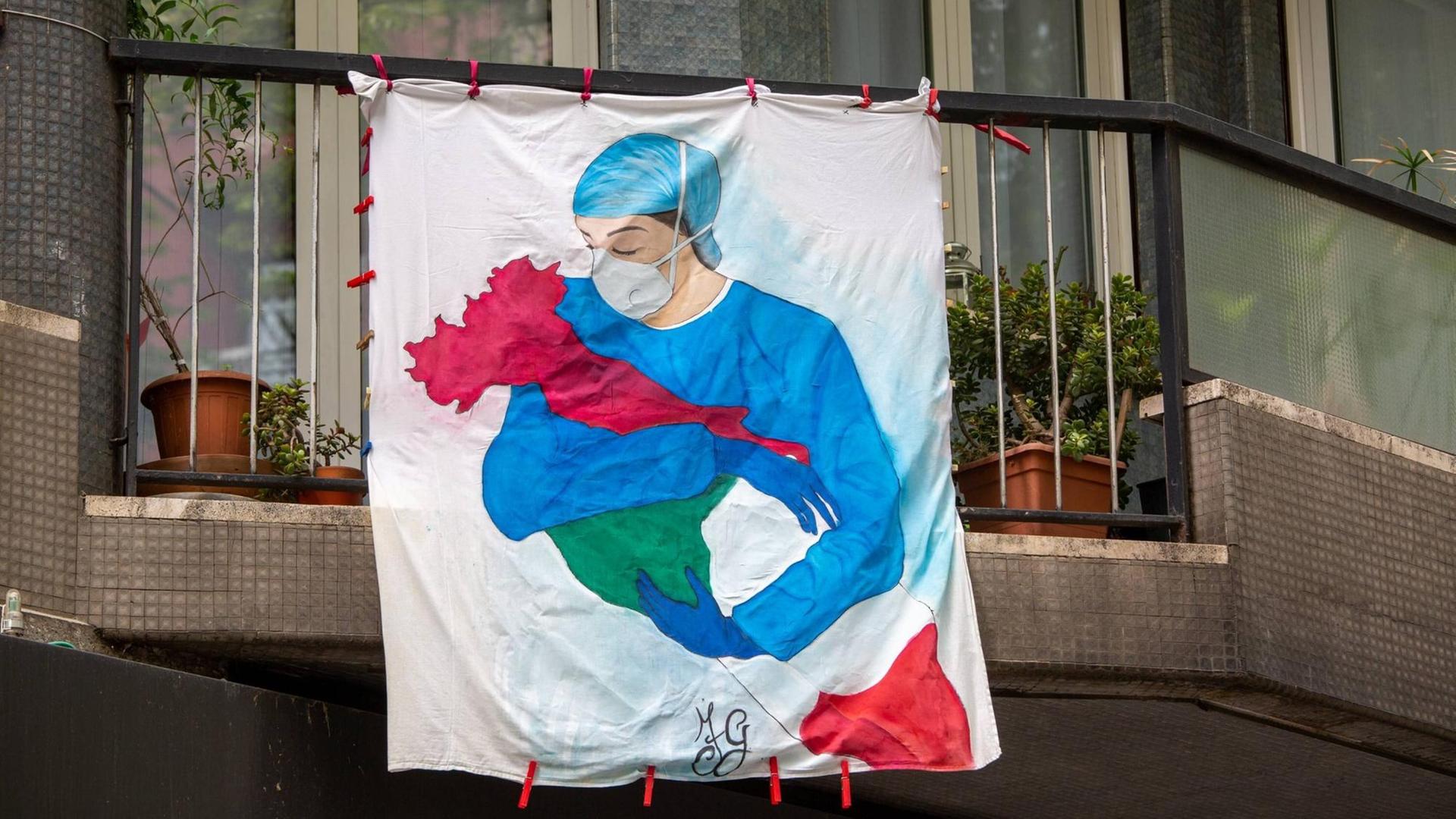 Flagge auf einem Balkon mit einer Pflegerin in Schutzkleidung erinnert an die Corona-Opfer in ganz Italien.
