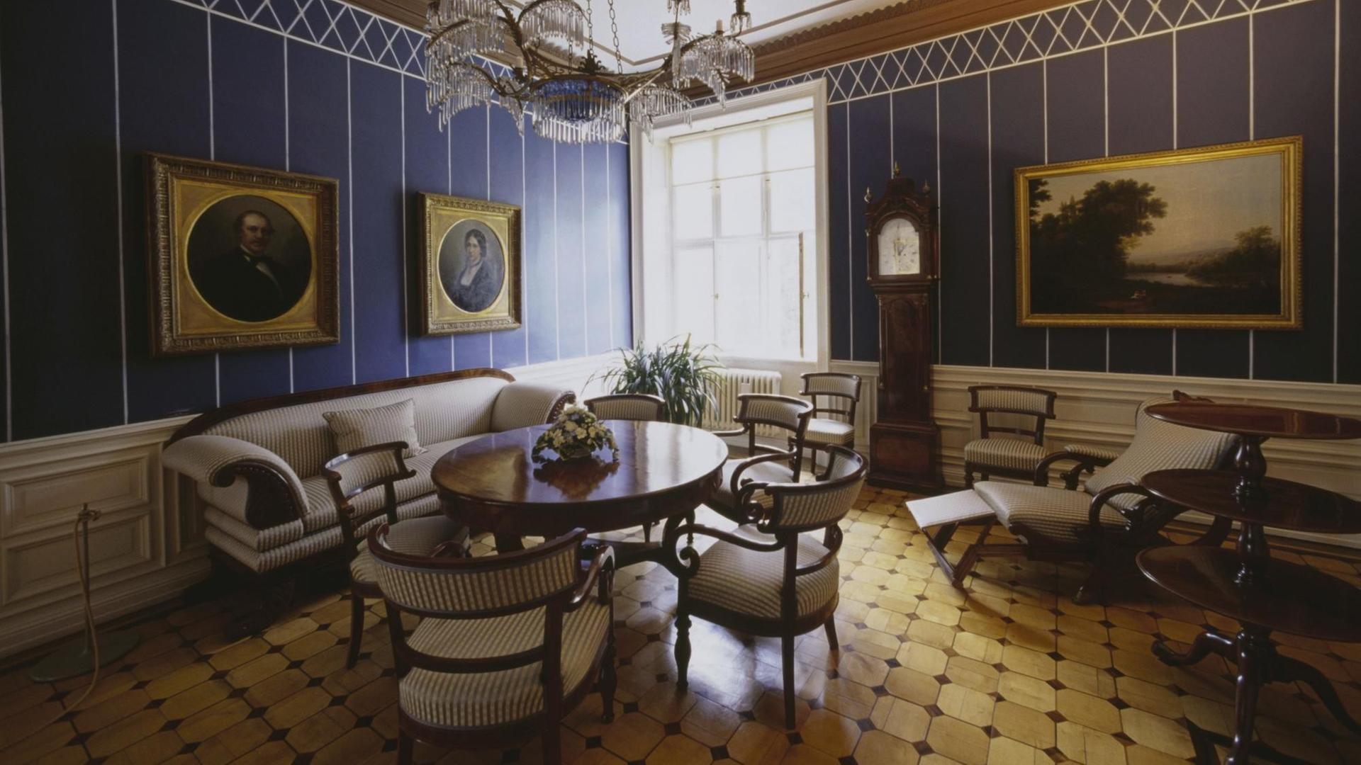 Blick in ein Wohnzimmer mit blauen Wänden und Parkettboden.