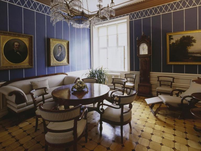 Blick in ein Wohnzimmer mit blauen Wänden und Parkettboden.
