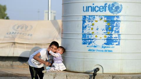 Ein Junge trägt am 18.10.2016 im Flüchtlingscamp Debaga zwischen Erbil und Mossul (Irak) seine kleine Schwester zu einem Wassertank, der von Unicef zur Verfügung gestellt wird.