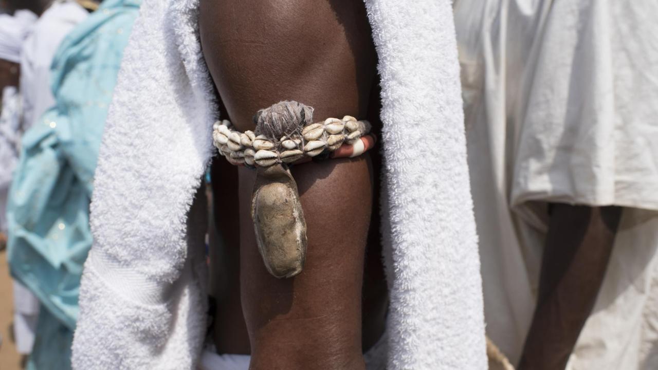 Ein Voodooanhänger trägt einen Fetisch und Muscheln am Arm (Bild: AFP / Stefan Heunis)
