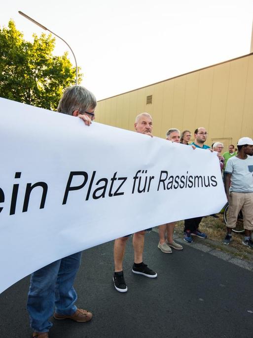 Menschen bei einer Mahnwache gegen Rassismus halten ein Plakat mit der Aufschrift "Kein Platz für Rassismus".