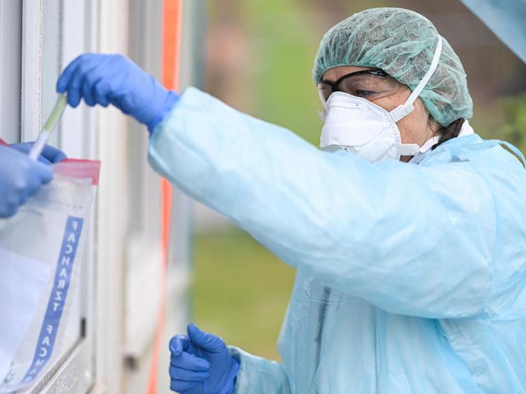 In einem Coronavirus-Testzentrum in Baden-Württemberg gibt eine Ärztin ein Abstrichstäbchen im Plastikröhrchen in einen Plastikbeutel.