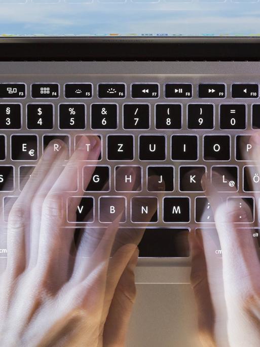 Eine Person tippt auf der Tastatur eines Laptop Computers.