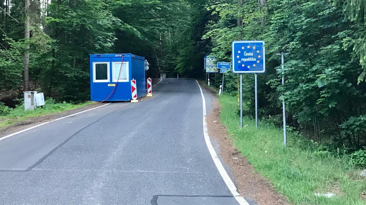 Auf einer Straße durch einen Wald steht ein blauer See-Container. Daneben ein Schild mit der Aufschrift "Tschechische Republik".