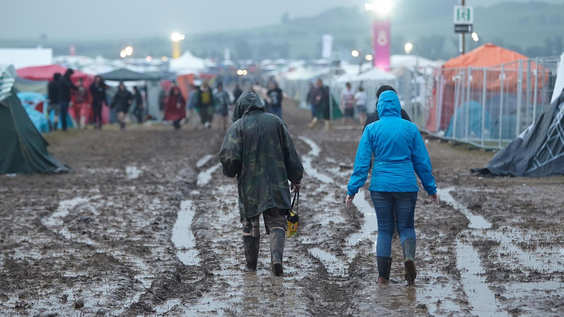 Festivalbesucher gehen am 03.06.2016 beim Festival "Rock am Ring" nach einem Gewitterregen über das aufgeweichte Gelände.