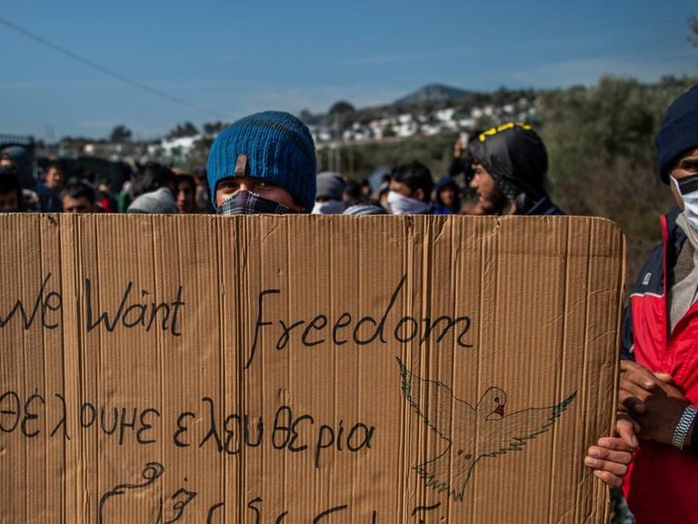 Ein Flüchtling hält ein Transparent mit dem Satz "we want freedom" in den Händen