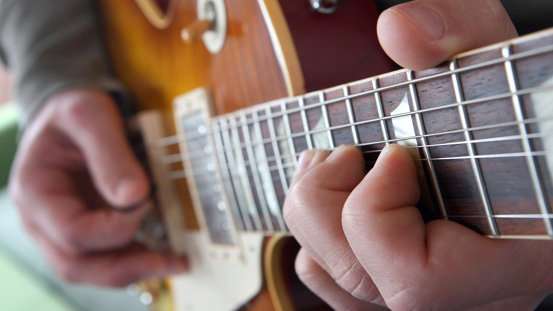 Ein Mann spielt auf einer elektrischen Gitarre, einer Gibson Les Paul.