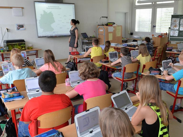Schüler der vierten Klasse der Grundschule "Wilhelm Busch" Altenburg sitzen in Altenburg (Thüringen) in einem interaktiven Klassenzimmer vor ihren Laptops.