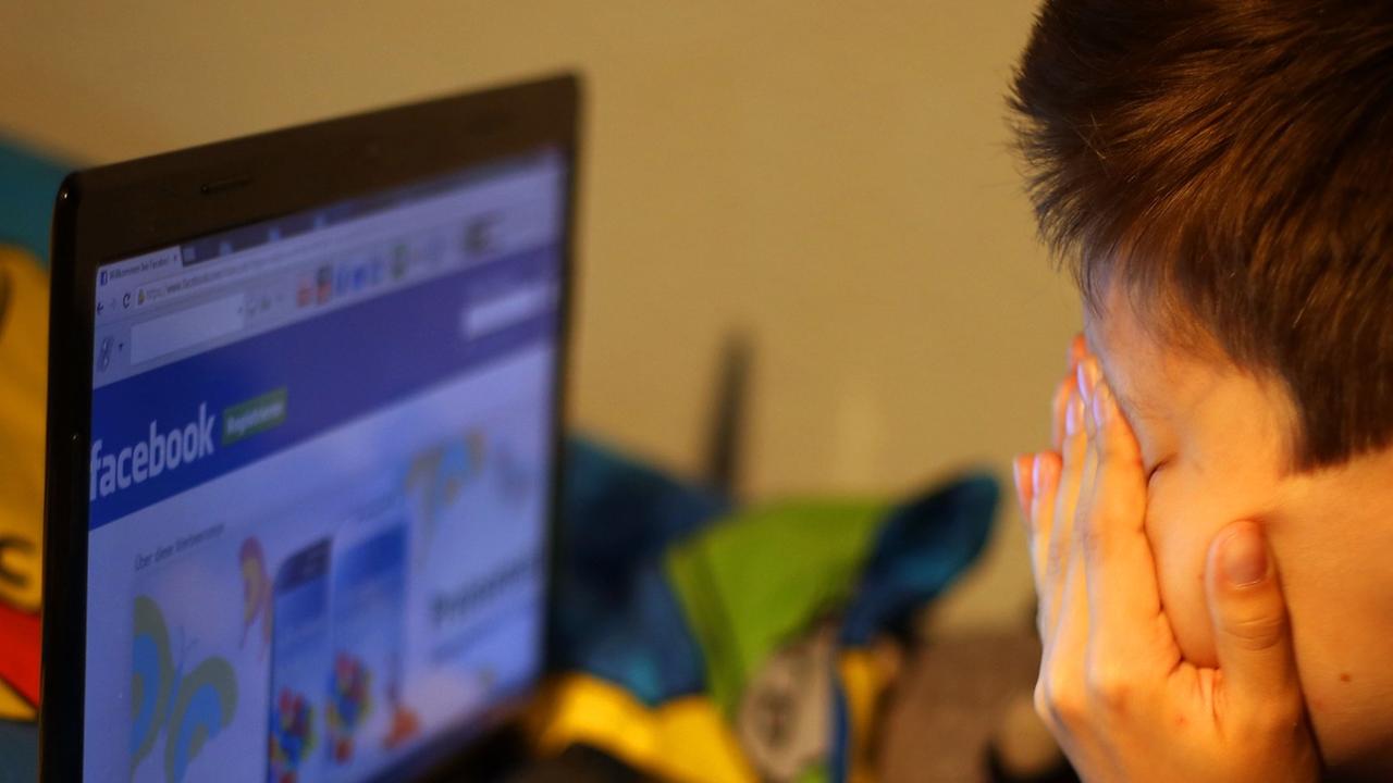 Ein Junge reibt sich am 15.05.2013 vor seinem Laptop beim betrachten der Facebook-Seite die Augen.
