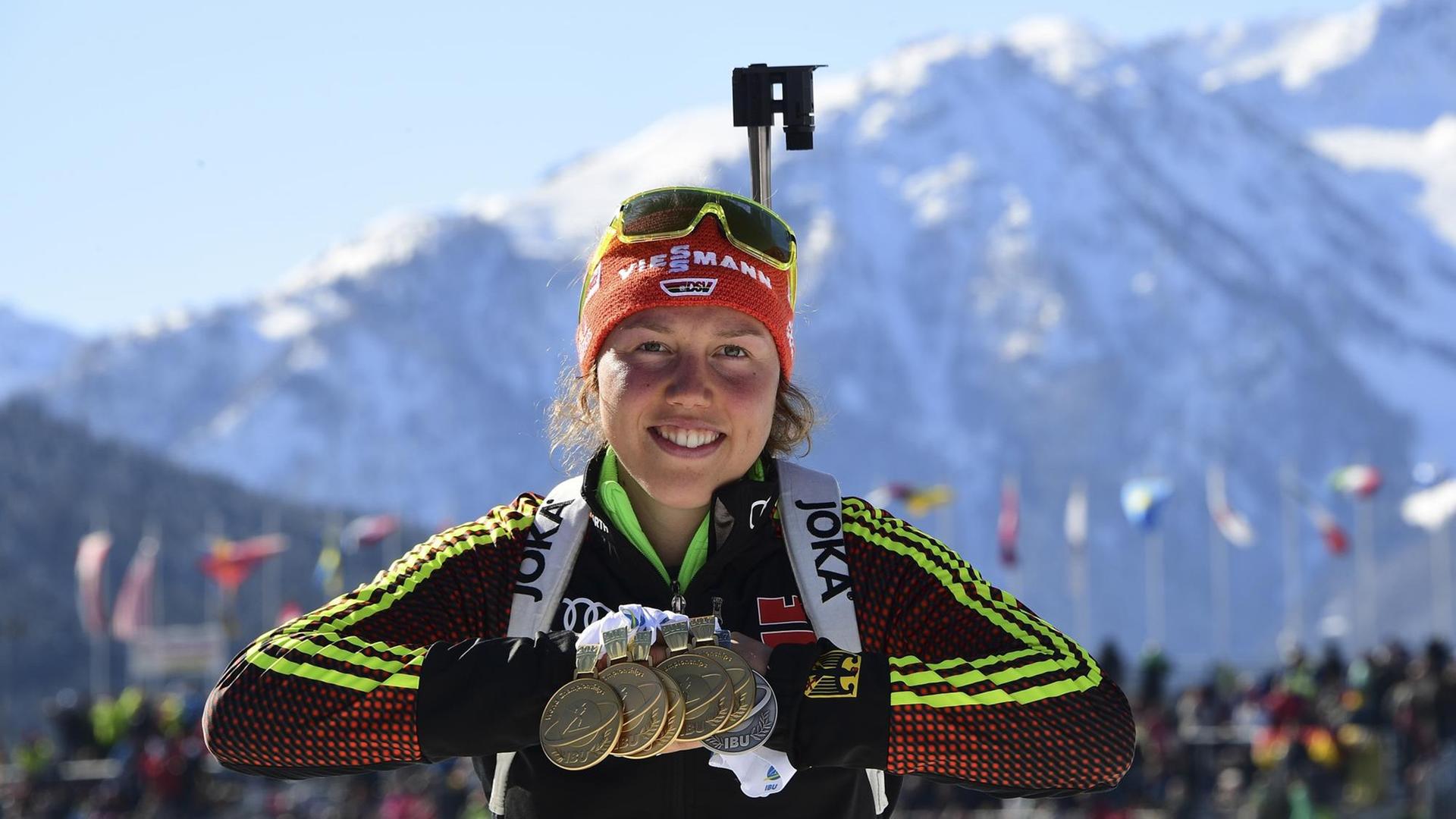 Dahlmeier steht vor dem schneebedeckten Berg und lächelt. Um ihren Hals hängen die sechs Medaillen.