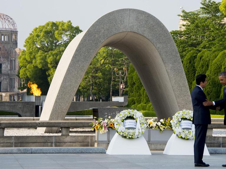 US-Präsident Barack Obama und Japans Premierminister Shinzo Abe schütteln sich im Friedenspark von Hiroshima die Hände, nachdem sie vor dem Mahnmal für die Opfer der Atombombe Kränze niedergelegt haben.