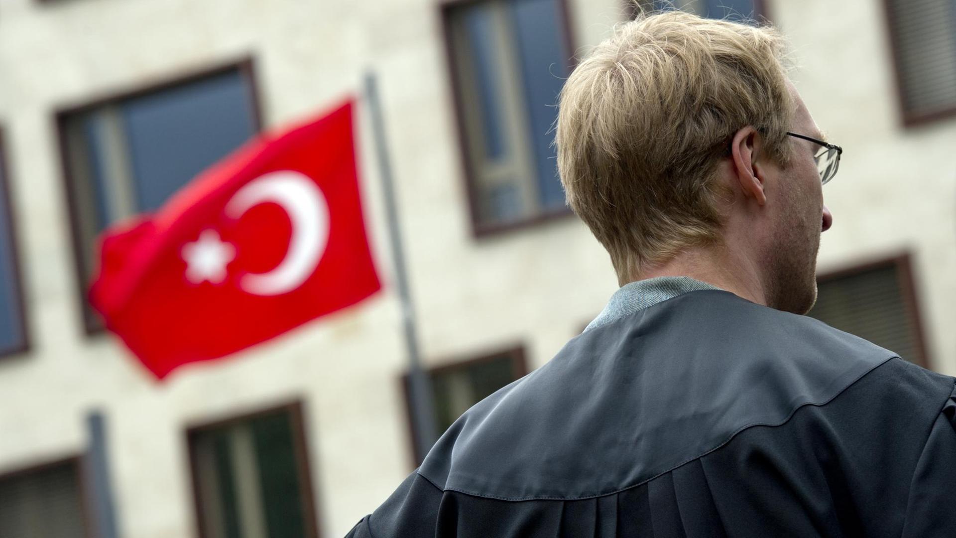 Eine türkische Flagge an einem Gebäude, vor dem ein Richter von hinten zu sehen ist.
