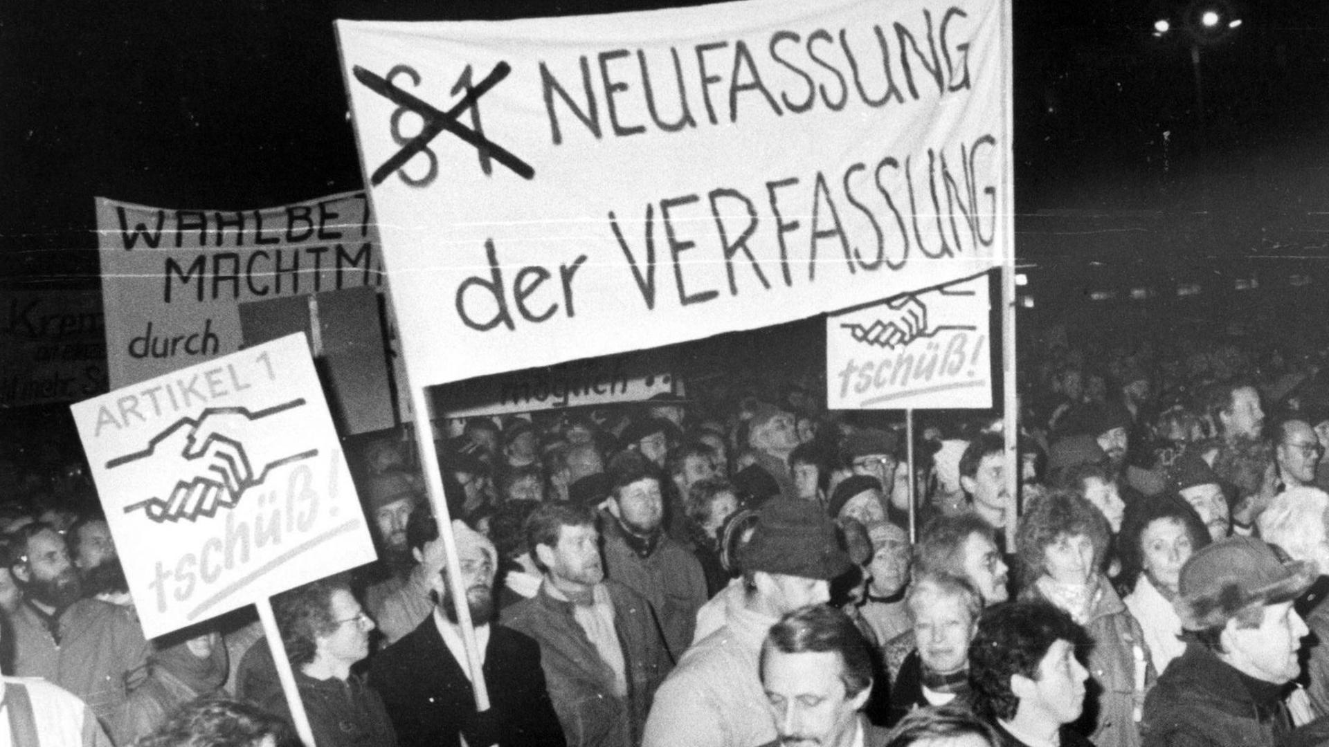 Montagsdemo in Dresden am 23. Oktober 1989. Menschen halten ein Banner mit dem Spruch "Neuverfassung der Verfassung" hoch.