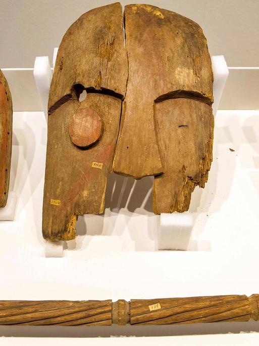Holzobjekte, vermutlich aus einer Grabplünderung in den 1880er Jahren. Das Ethnologische Museum Berlin hat die Objekte 2018 zurückgegeben. Bei der Restitution an die Chugach Alaska Corporation handelte es sich um die erste Rückgabe in der mehr als 100-jährigen Geschichte des Ethnologischen Museums an eine Herkunftsgesellschaft.