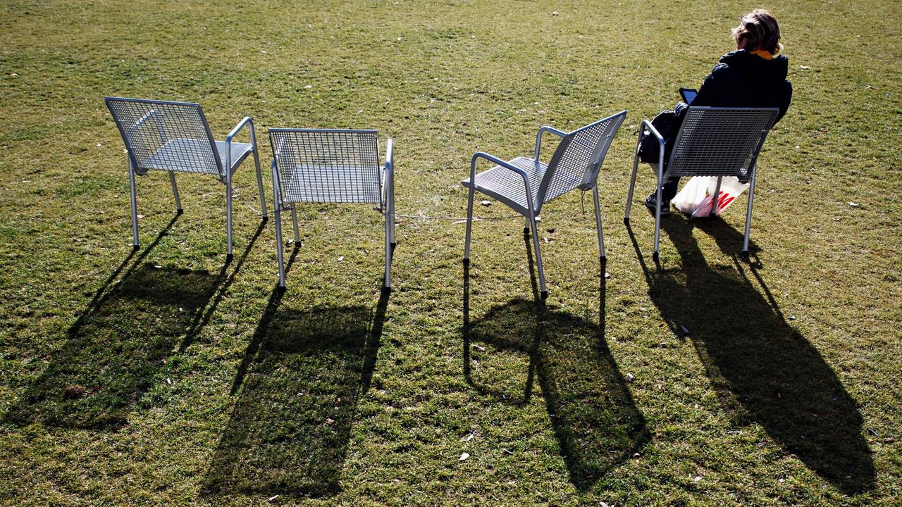 Eine Frau sitzt am 17.02.2014 in München (Oberbayern) bei Sonnenschein auf einem Stuhl. Milde Temperaturen und sonniges Wetter laden zum Sonnenbaden ein. 