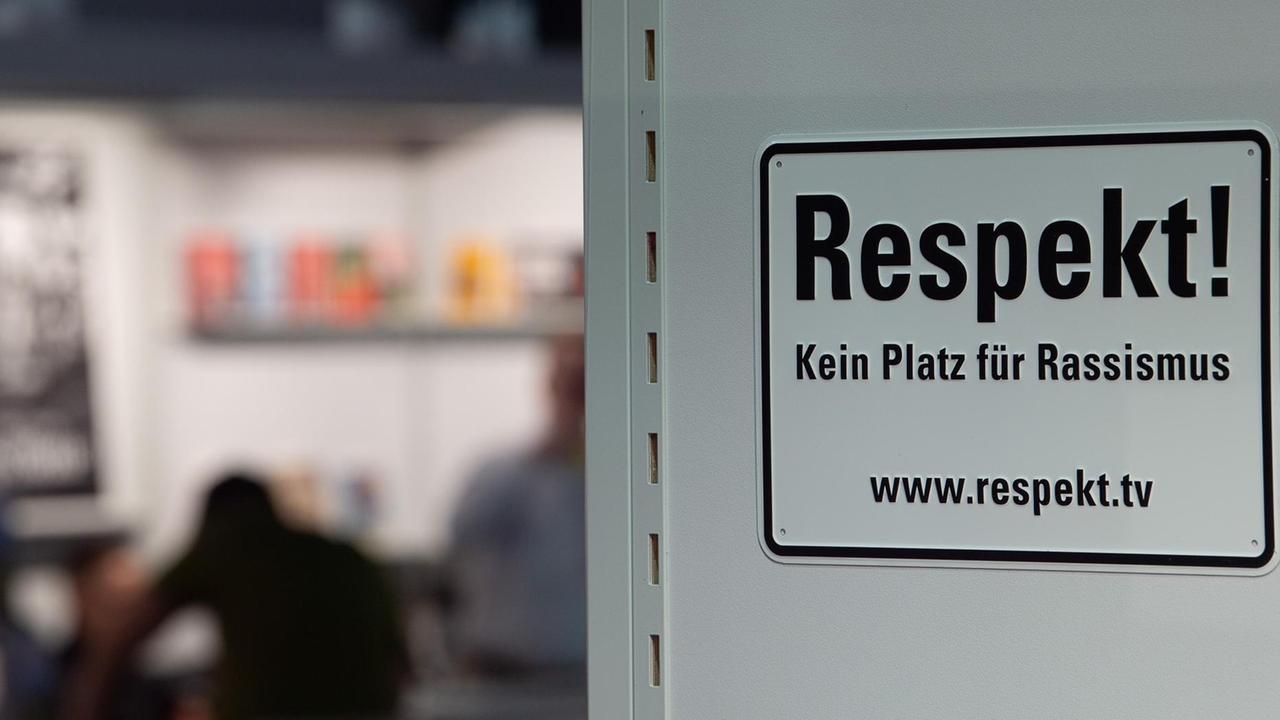 "Respekt! Kein Platz für Rassismus", heißt es auf einem Schild. Im Hintergrund: Stand des umstrittenen Jungeuropa-Verlages auf der Frankfurter Buchmesse.