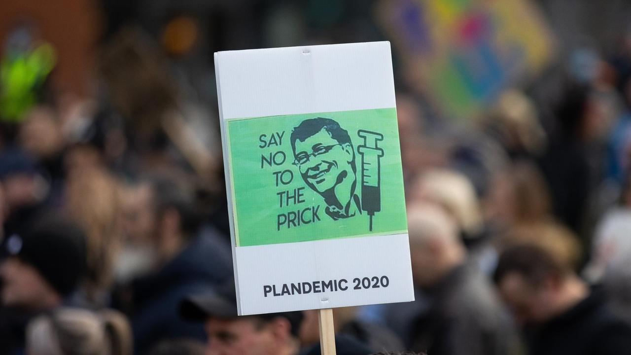 Bei einer Demonstration in England wird ein grünes Schild hochgehalten, auf dem der Kopf von Bill Gates und eine Spritze abgebildet sind.