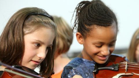 Naomi (l) und Joyce probieren am Dienstag (26.08.2008) ihre neuen Geigen aus, die der Bundespräsident zuvor an Grundschüler der Martin-Luther-Grundschule im Rahmen der Initiative «Jedem Kind ein Instrument» in Gelsenkirchen übergab.