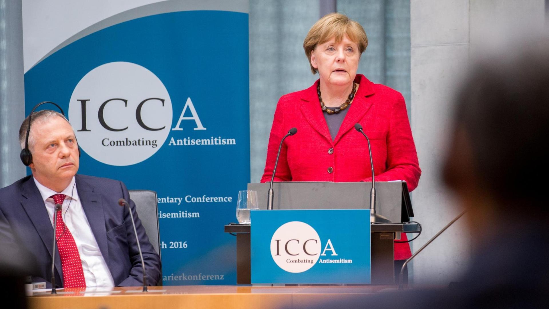 Bundeskanzlerin Angela Merkel (CDU) spricht am 14.03.2016 bei der ICCA Antisemitismus Konferenz in Berlin neben dem Vorsitzenden der ICCA, John Mann.