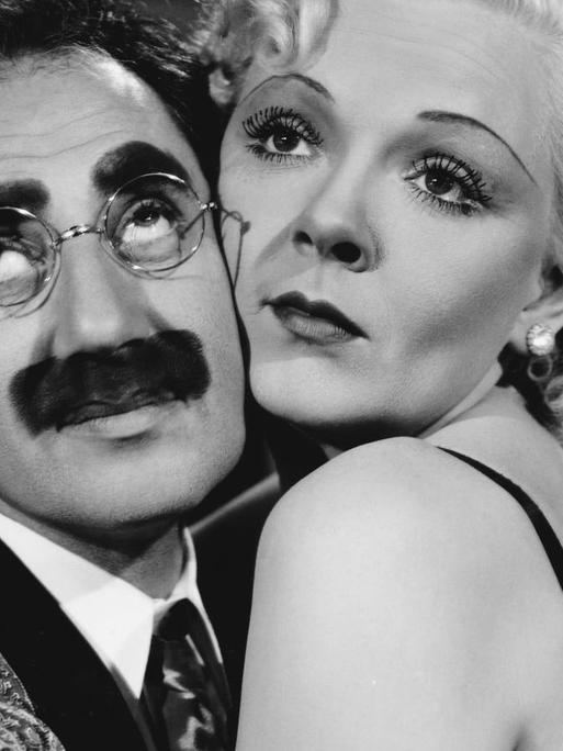 Groucho Marx und Esther Muir sitzen umschlungen auf einer Couch.