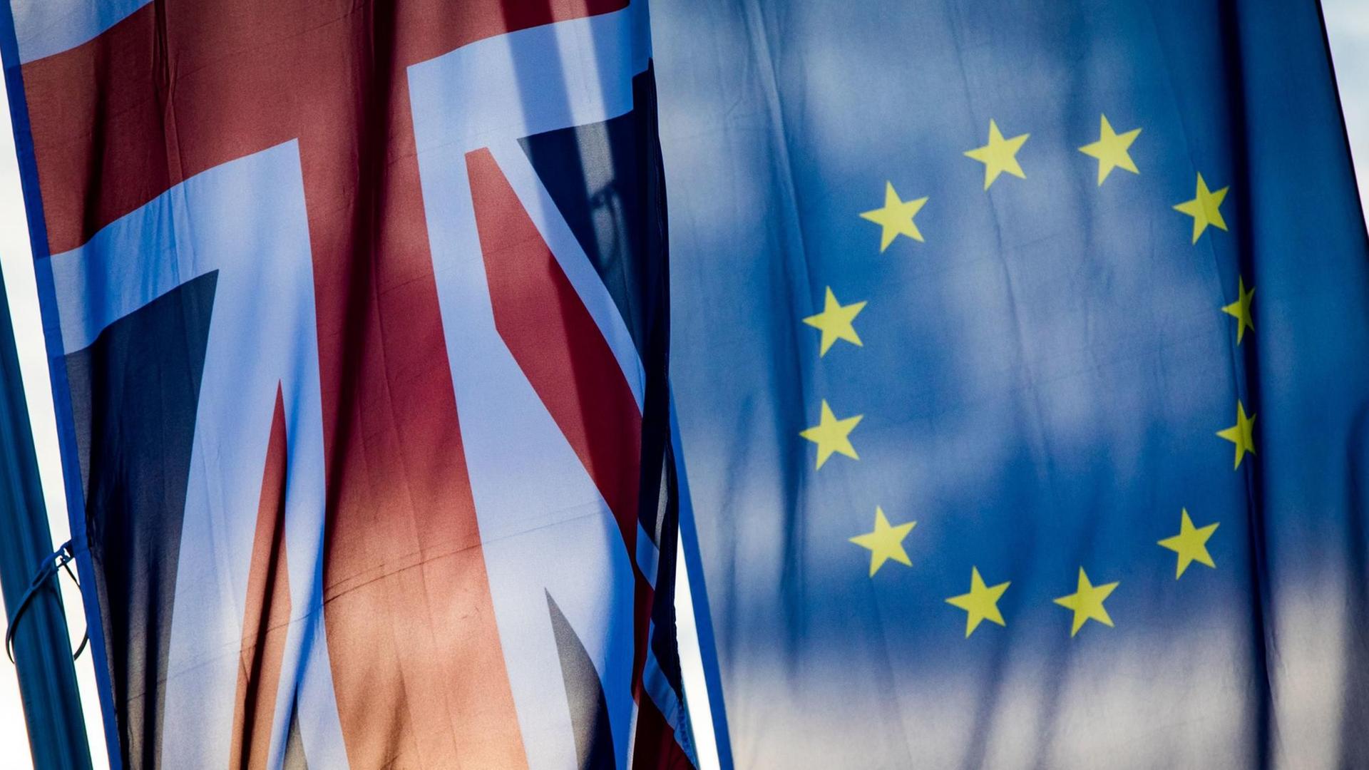 Eine britische (l.) und eine EU-Fahne (r) hängen nebeneinander an einem Mast.
