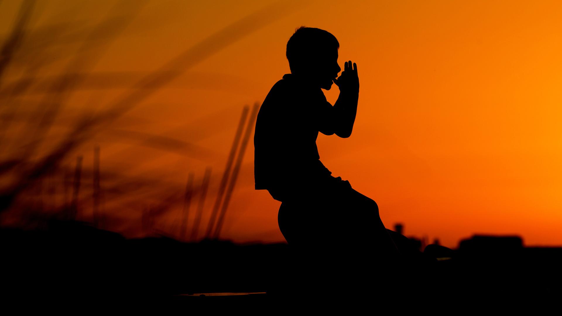 Ein Junge spielt im Sonnenuntergang auf Spielgeräten am Strand an der Ostseeküste