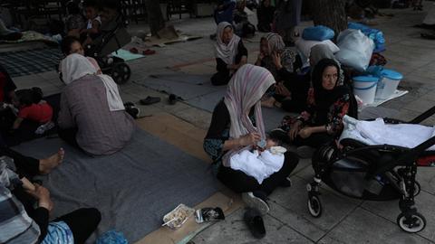 Flüchtlingsfrauen mit Kopftüchern sitzen auf Kartons und Decken auf dem Viktoria-Platz in Athen.