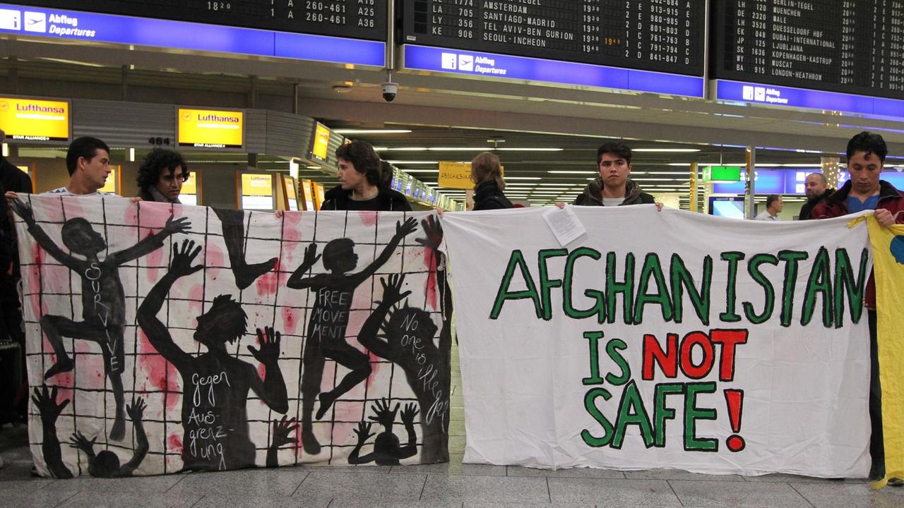 Demonstranten halten am Flughafen in Frankfurt am Main Transparente, auf einem steht "Afghanistan is not safe", also "Afghanistan ist nicht sicher".
