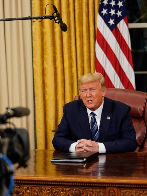 US-Präsident Donald Trump hat die Einreisesperren für Menschen aus dem europäischen Schengenraum in einer Fernsehansprache verkündet. Eine Kamera filmt ihn an seinem Schreibtisch im Oval Office im Weißen Haus in Washington.