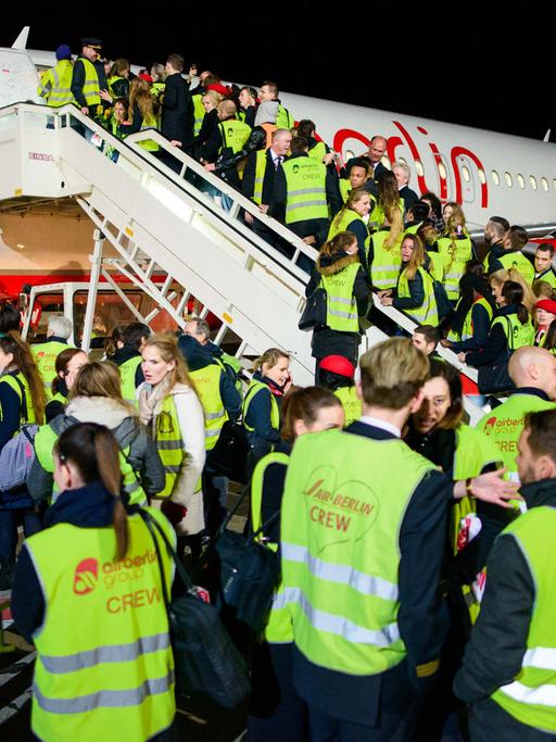 Mitarbeiter der Fluggesellschaft Air Berlin stehen am 27.10.2017 auf dem Vorfeld des Flughafen Berlin-Tegel nach der Landung der letzten Maschine der Airline auf einer Fluggasttreppe.