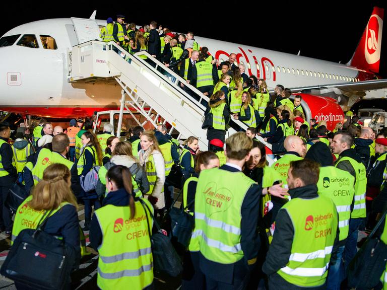 Mitarbeiter der Fluggesellschaft Air Berlin stehen am 27.10.2017 auf dem Vorfeld des Flughafen Berlin-Tegel nach der Landung der letzten Maschine der Airline auf einer Fluggasttreppe.