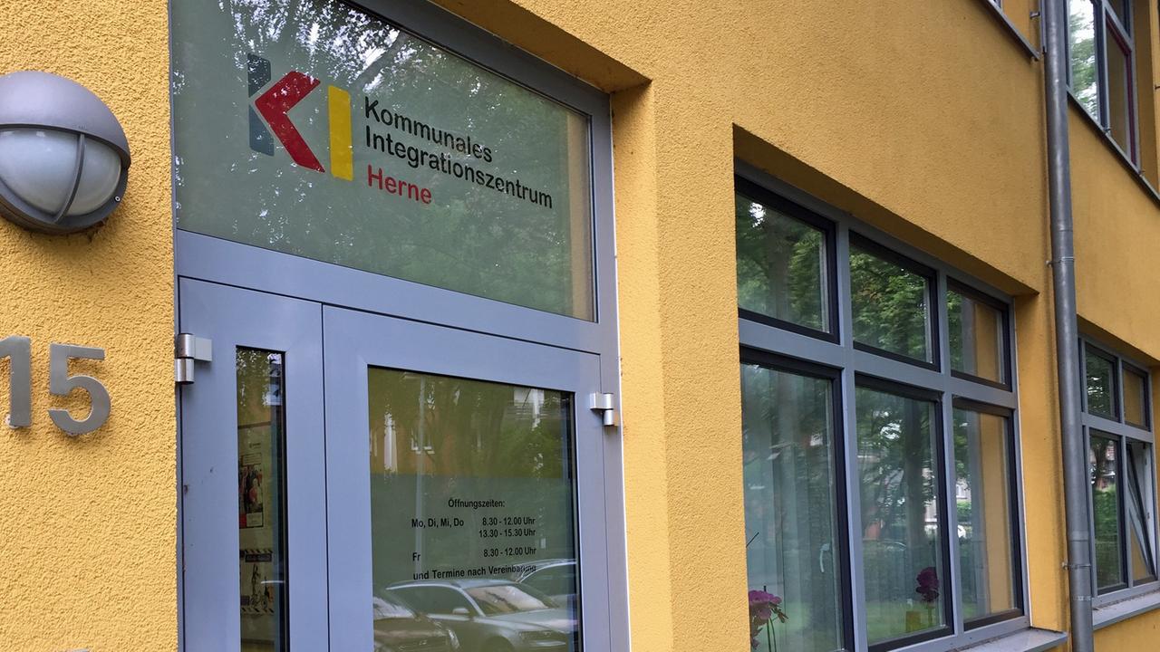 Hausfassade des Kommunalen Integrationszentrum Herne. Gelbes Haus mit dem Schriftzug "Kommunalen Integrationszentrum Herne" auf dem Fenster über der Haustür.