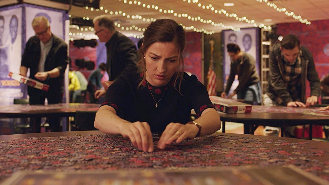 Eine Frau sitzt an einem Tisch und löst gebannt ein Puzzle.