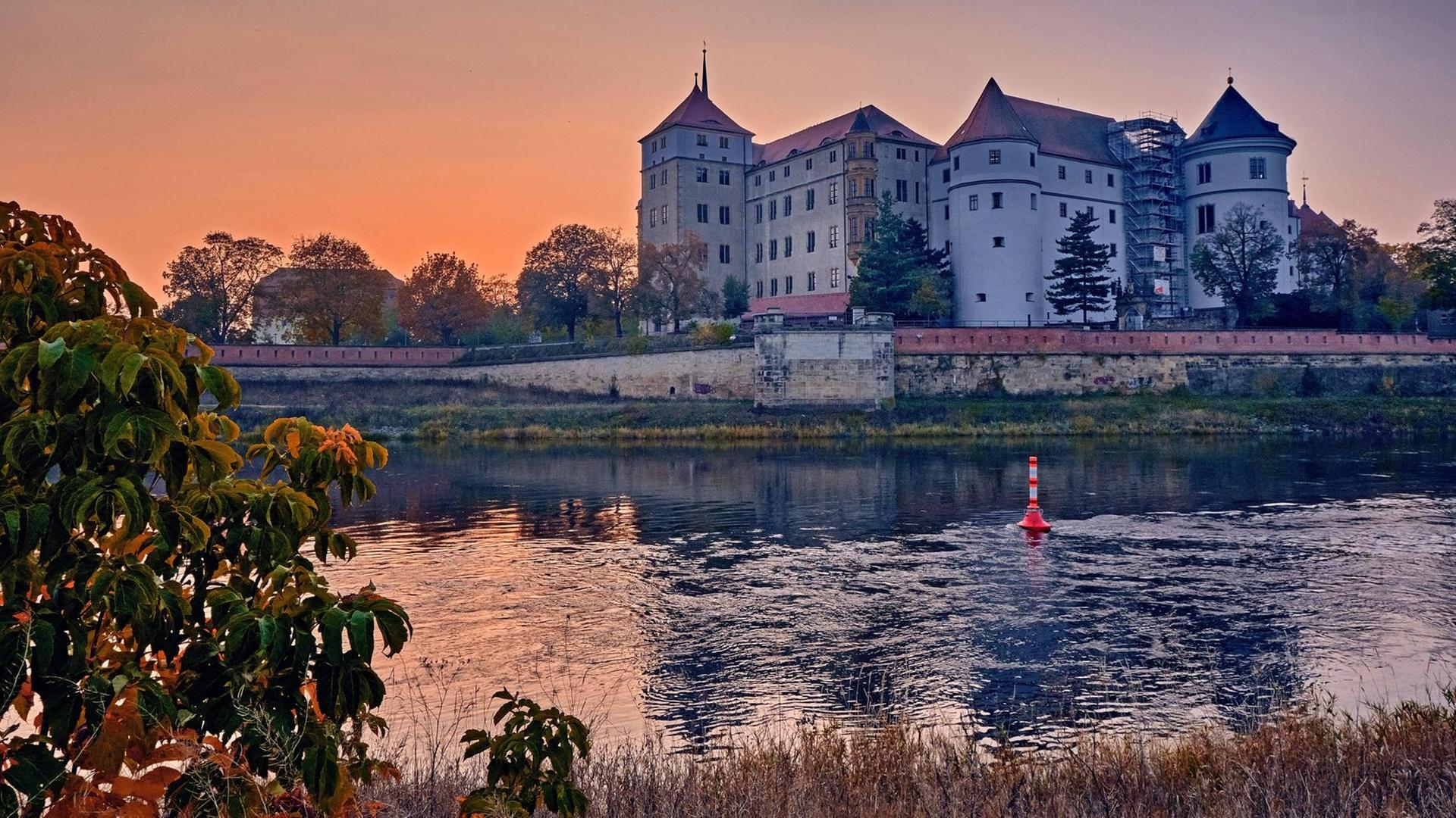 Das Schloss Hartenfels im Sonnenuntergang am Ufer der Elbe in Torgau.