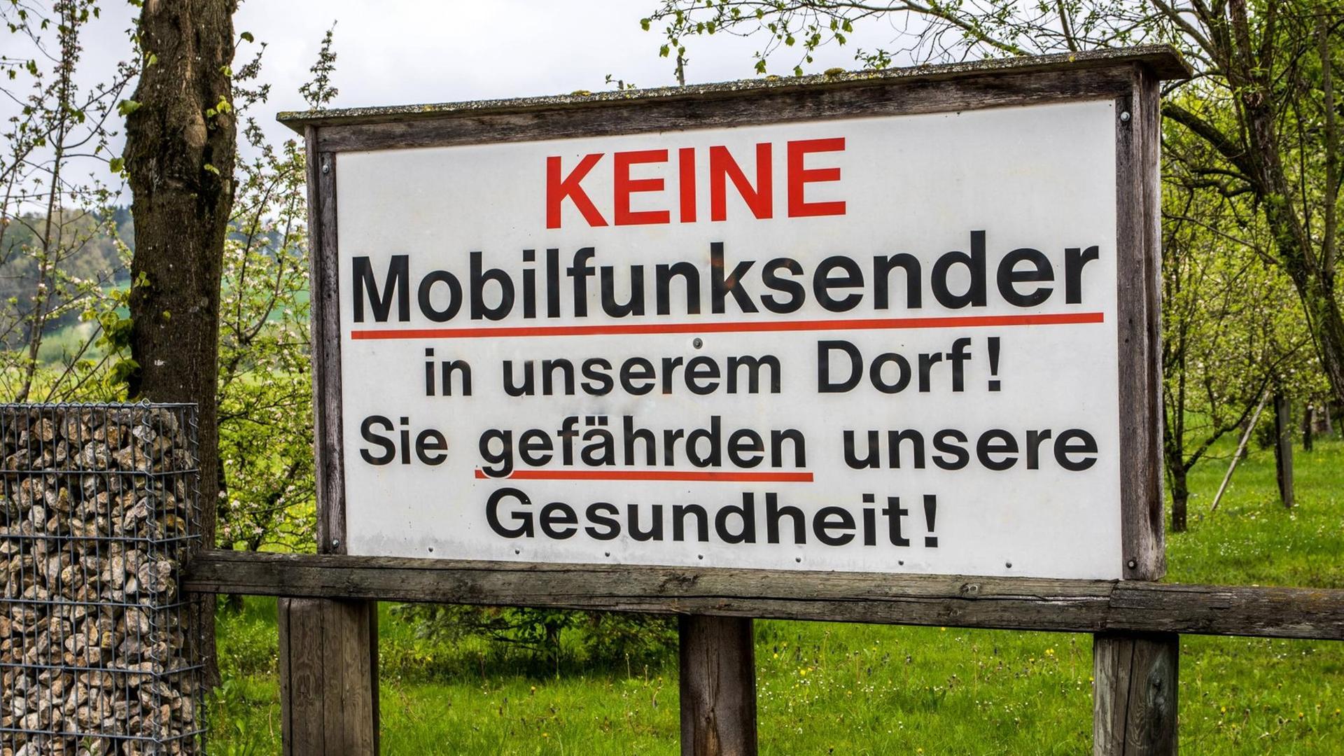 Auf einem Protestschild steht: Keine Mobilfunksender in unserem Dorf! Sie gefährden unsere Gesundheit!
