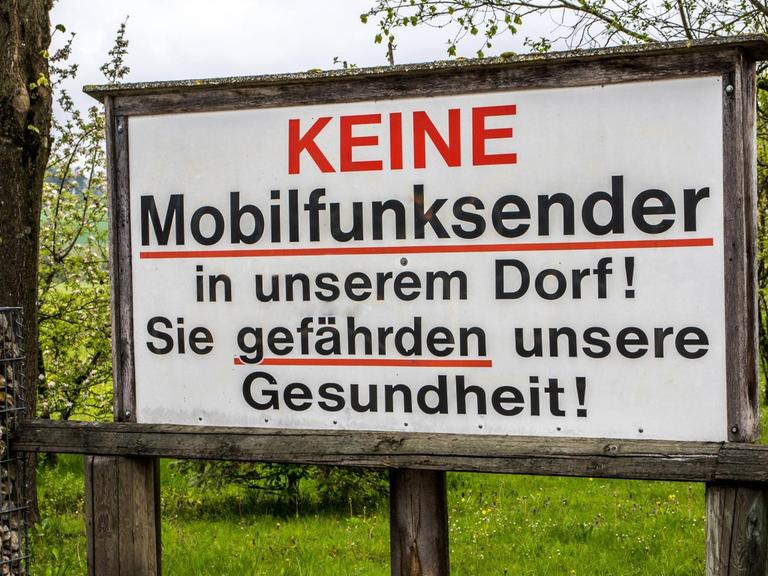 Auf einem Protestschild steht: Keine Mobilfunksender in unserem Dorf! Sie gefährden unsere Gesundheit!