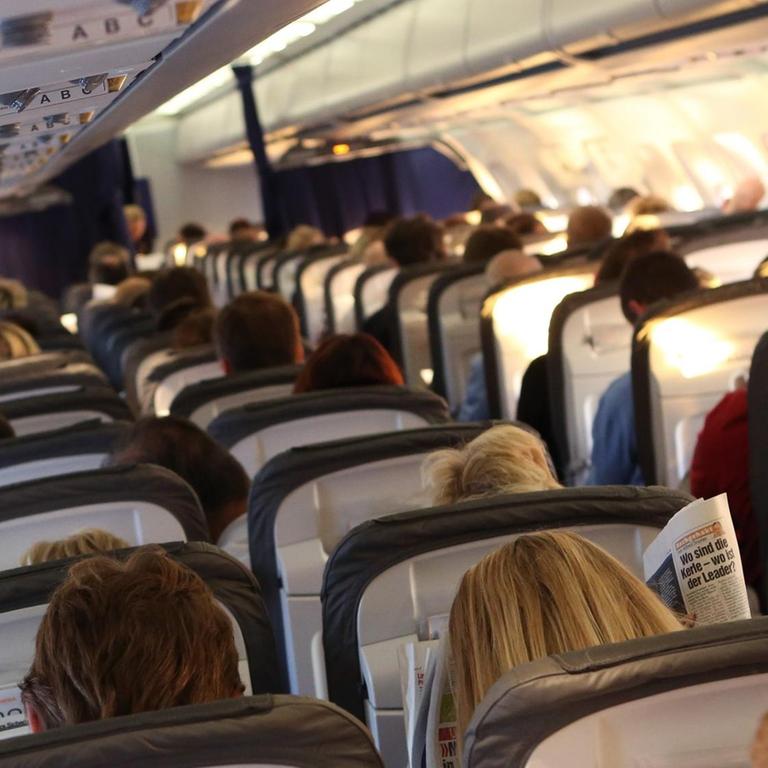 Reisende sitzen in der Kabine einer Maschine der Lufthansa.