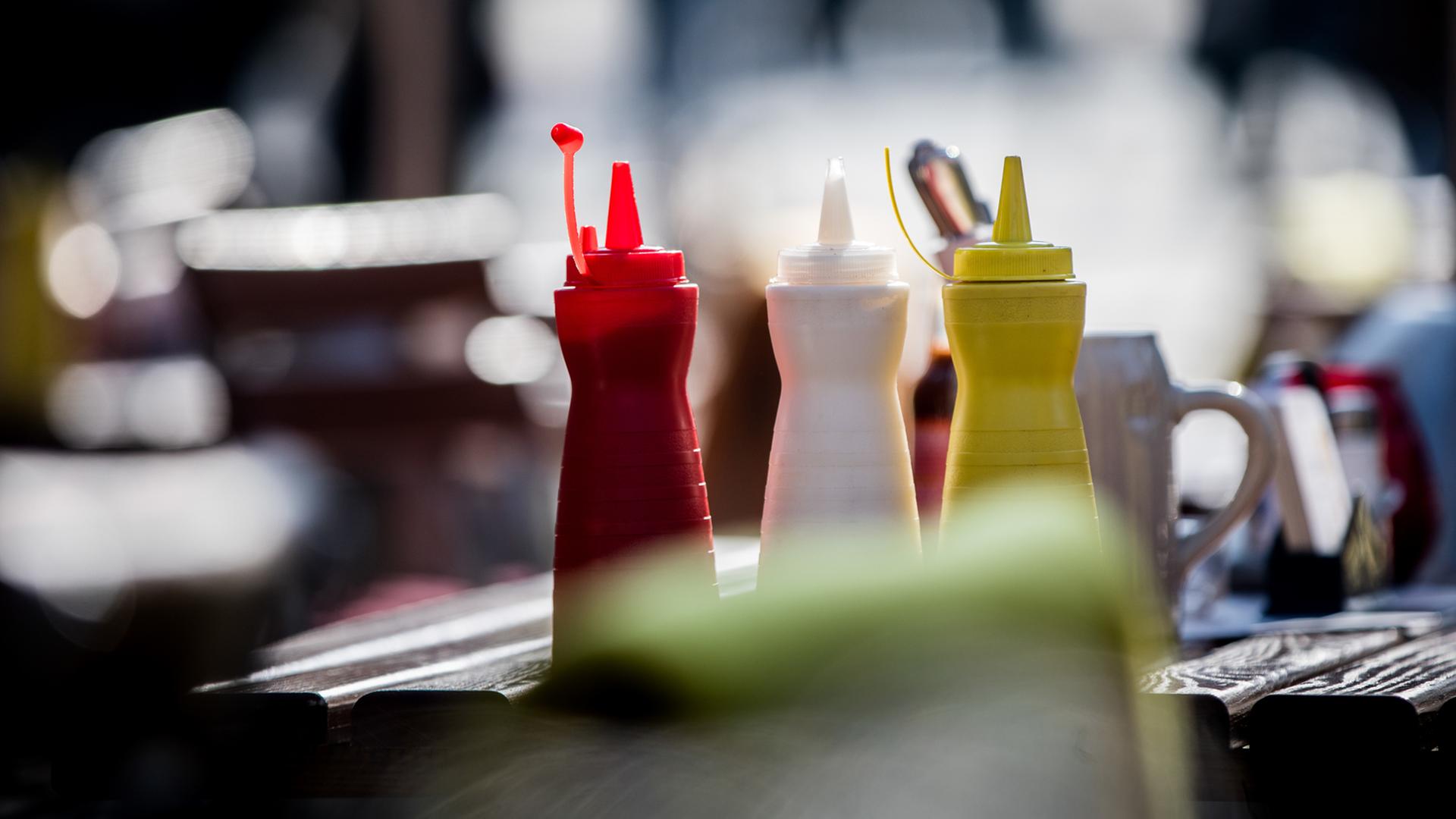 Plastikflaschen mit Ketchup, Mayonnaise und Senf stehen am 14.02.2017 in Frankfurt am Main (Hessen) auf dem Paulsplatz auf dem Tisch eines Straßenlokals, das sich auf das Servieren von Pommes Frites und Würtschen spezialisiert hat.