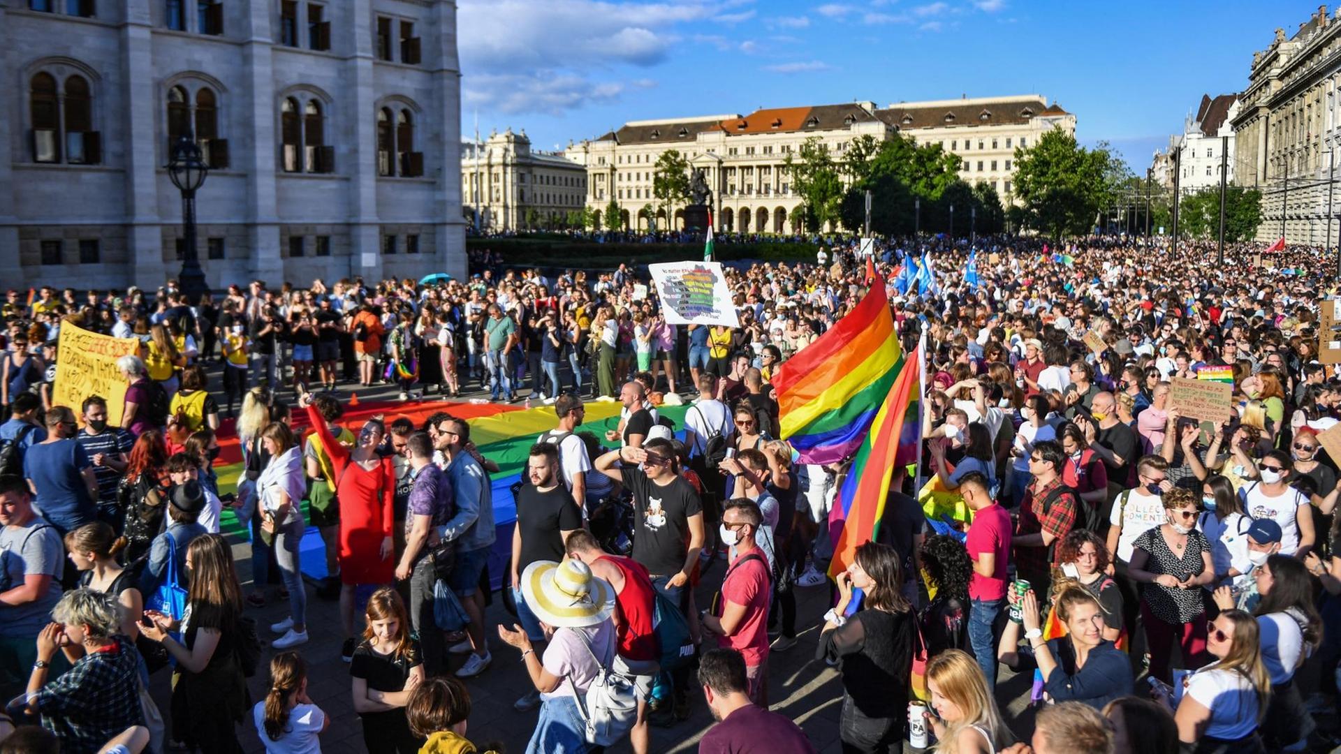 Eine Menschenmenge mit Regenbogen-Fahnen steht am Parlamentsgebäude
