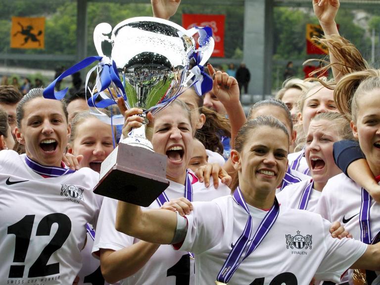 Jubelnde Frauen der Mannschaft des FC Zürich halten einen Pokal in die Luft.