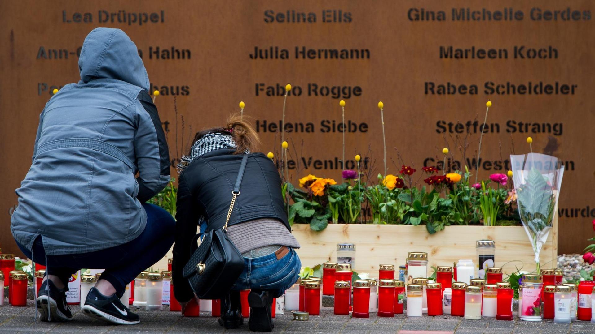 Eine Frau und ein Mann zünden in Haltern am See (Nordrhein-Westfalen) vor der Gedenktafel am Joseph-König-Gymnasium die mitgebrachten Kerzen an.