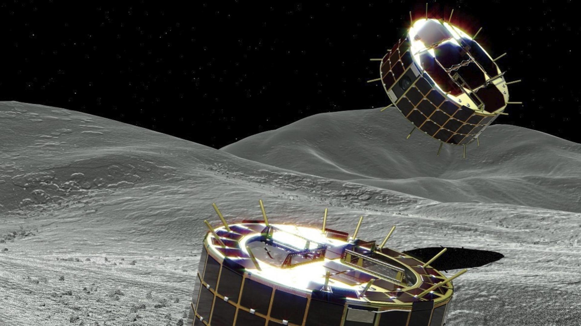 Die Computergrafik zeigt zwei zylinderförmigen und solarbetriebene Rover auf einem Asteroiden.